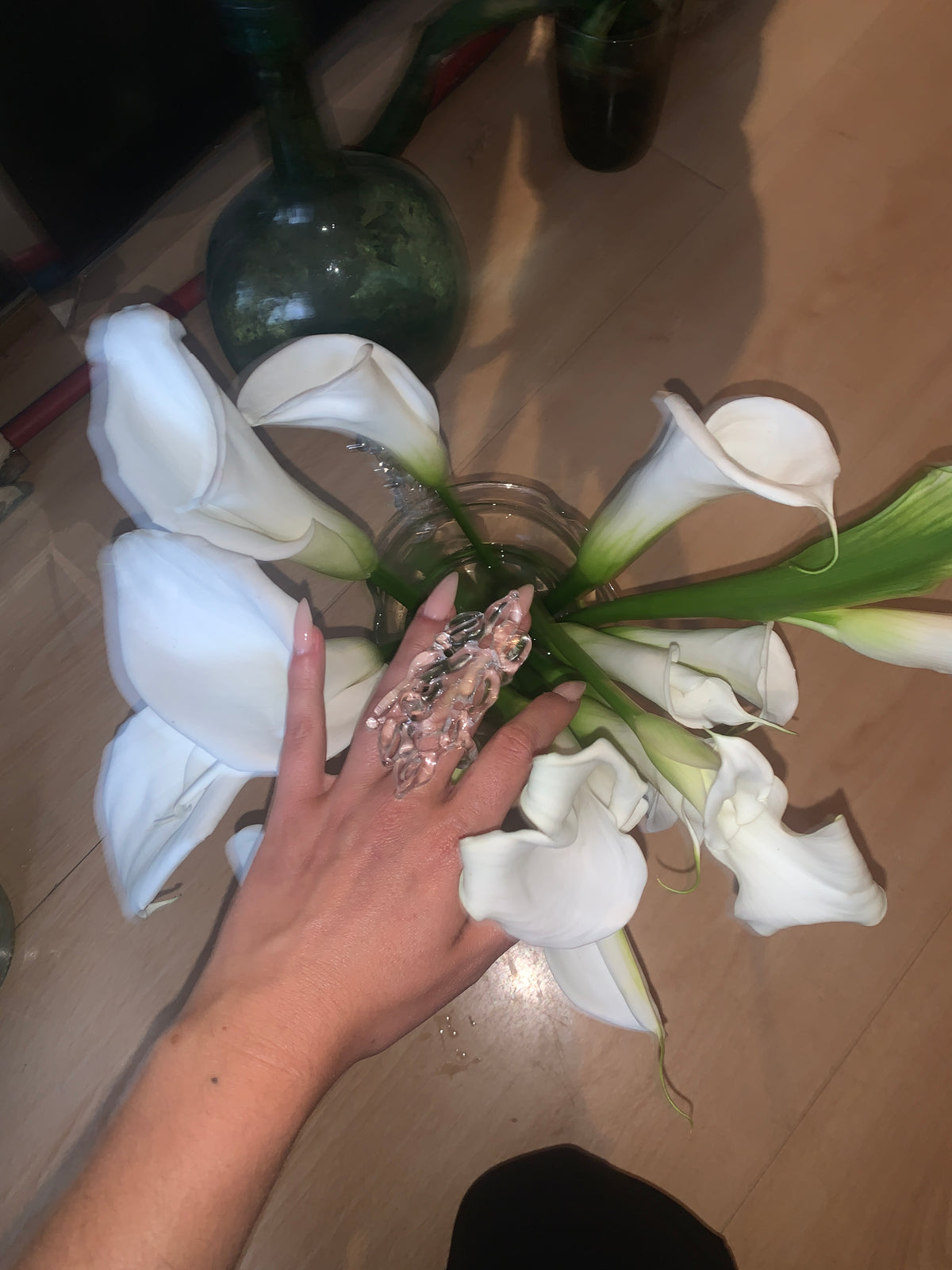 Thorn Glass Ring 0134 in clear hand-sculpted borosilicate glass, worn on the hand among calla lilies, Rain and Rivers