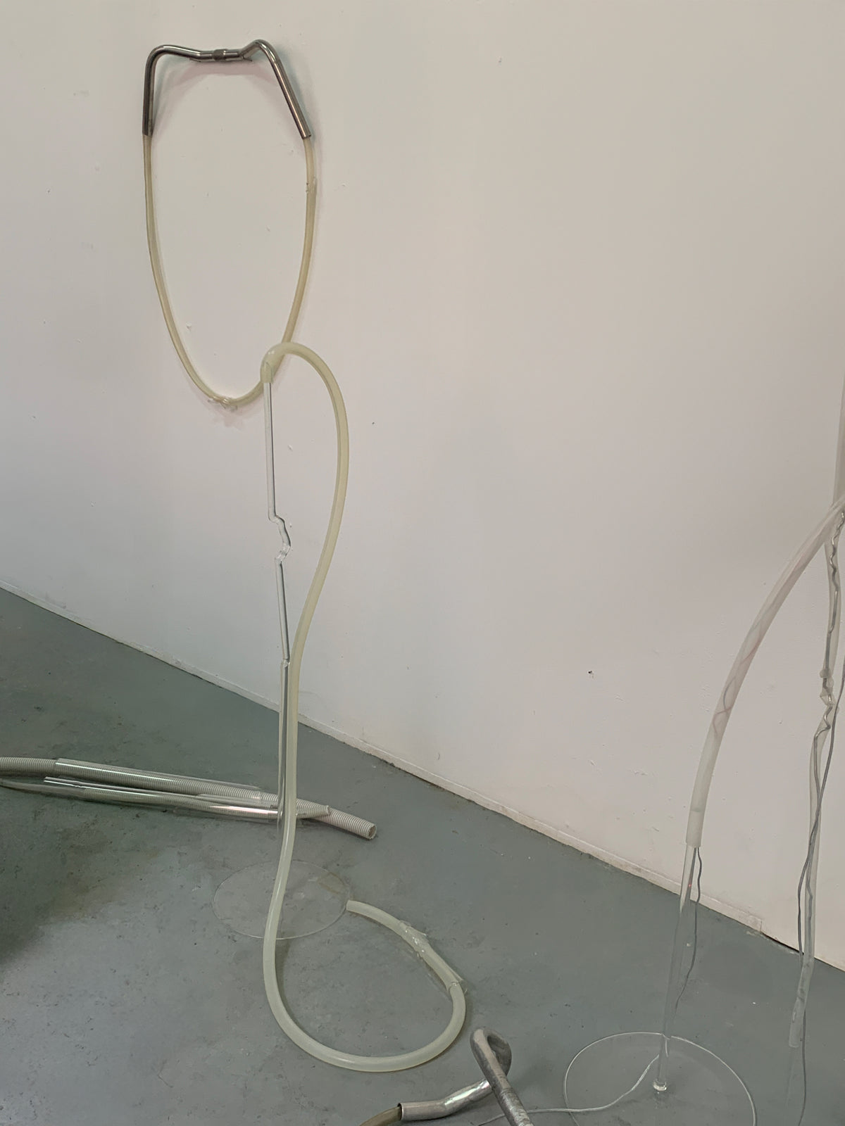 Looped blown glass tube hanging from the wall down to the studio floor